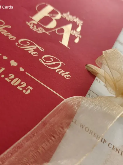 A close-up of the red "Save The Date" invitation, showing the organza ribbon and the vellum insert with the event details.