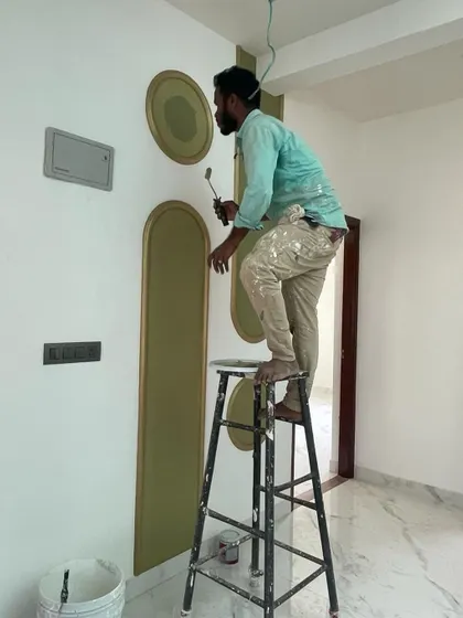 A painter carefully applies gold trim to the decorative wall panels. This behind-the-scenes shot emphasizes the manual skill and attention to detail required to execute our intricate designs.