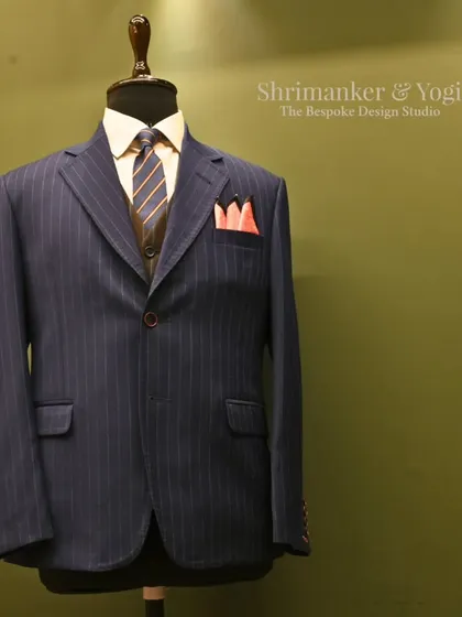 Another perspective of the classic navy pinstripe suit, this time with our studio logo. This composition reinforces our brand's commitment to timeless menswear and meticulous styling.