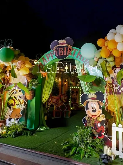 A different angle of the safari entrance at night, highlighting the depth and layers of the decoration, from the white picket fence to the animal props.