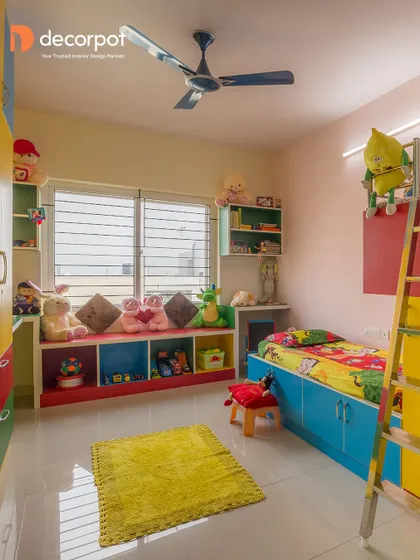 A colorful and playful kid's room designed for fun and function. It features a low bed with storage, a bay window seat with toy cubbies, and a bunk bed ladder, making the most of the space.
