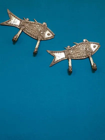 Whimsical fish-shaped wall hooks add a touch of local artistry and playfulness to a vibrant blue wall at Jalakara.