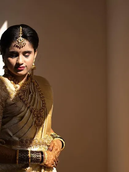 A moment of quiet reflection for the bride. The soft light highlights the smooth finish of her foundation and the rich color of her lipstick, essential for a classic bridal look.