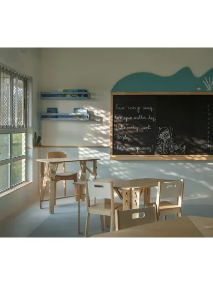 The blackboard in the aqua classroom is topped with a wave-like wooden cutout, continuing the underwater theme. Natural light filters in, creating a bright and cheerful atmosphere for learning.