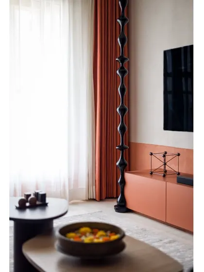 The TV wall features a modern, glossy black wooden turning that contrasts beautifully with the matte, textured wall.