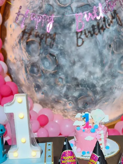 The cake is the centerpiece of any birthday. This beautiful pink cake sits perfectly within the moon-themed decor, complete with a light-up number '1' and themed party hats.