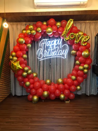 A vibrant red and gold balloon ring perfect for a birthday celebration. The "Happy Birthday" neon sign and a "love" foil balloon add a personal and festive touch.