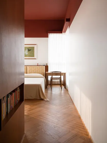 A peek into a kids' bedroom filled with light, color, and personality. The rich oak herringbone floor is complemented by a deep red ceiling, creating a space that is both playful and sophisticated.