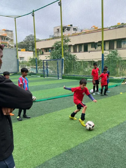A coach observes a young player's technique during a U9 preseason training drill, providing personalized guidance.