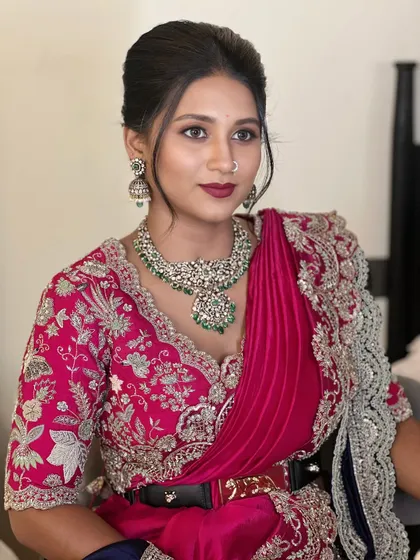 This look is a beautiful blend of modern and traditional. The makeup is fresh and elegant, with a bold lip that complements the vibrant pink outfit and classic diamond jewelry.
