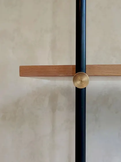A detail shot of a custom shelving unit, where a simple brass knob secures a wooden shelf to a metal rod. This highlights our belief that even the smallest details contribute to the overall integrity of the design.