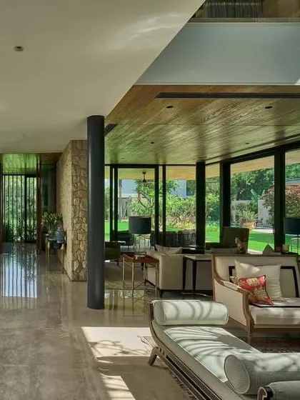 The interior living space of the 'Patio House' is defined by transparency, with floor-to-ceiling glass offering uninterrupted views of the garden.