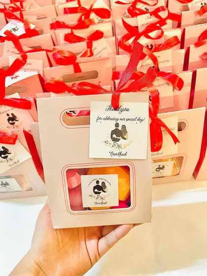 Holding up the anniversary favor box to showcase its design and personalized details.