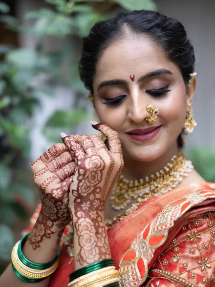 A close-up of the traditional Maharashtrian bridal look, featuring beautiful henna and classic gold jewellery with the orange Nauvari saree.