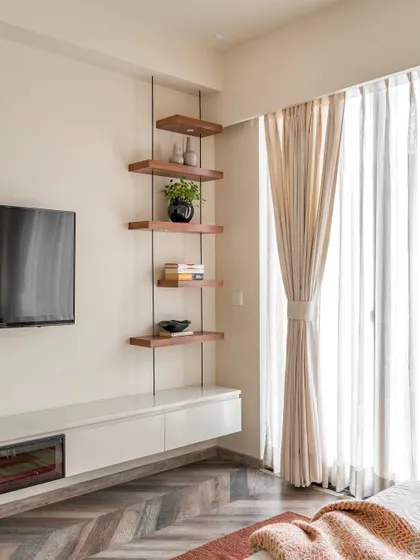 The TV and storage unit in the 'Project Lily' bedroom. We designed a floating white console and a set of suspended wooden shelves to create a display corner that is both stylish and functional.