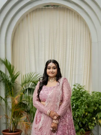 A full portrait of the bride in her pastel lehenga. The makeup is designed to be soft and radiant, letting her natural beauty and happiness be the focus.