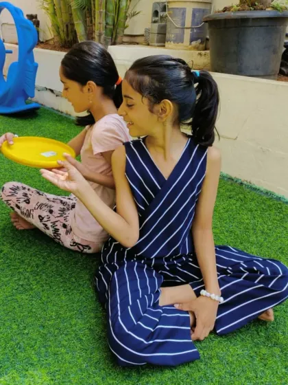 Two girls participate in a partner exercise with a frisbee. Our morning exercises are designed to be interactive and fun.