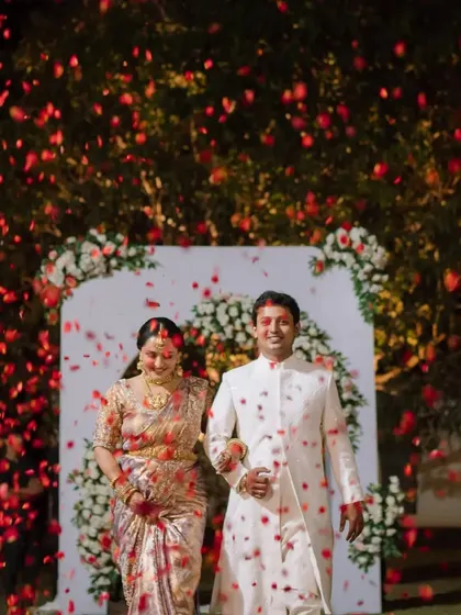 The bride and groom walk hand-in-hand, showered with rose petals as they make their exit from their beautiful evening wedding ceremony.