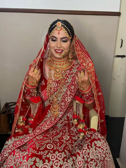 The smile of a happy bride says it all. Here she is, looking radiant in her red wedding lehenga, with makeup that enhances her joy.