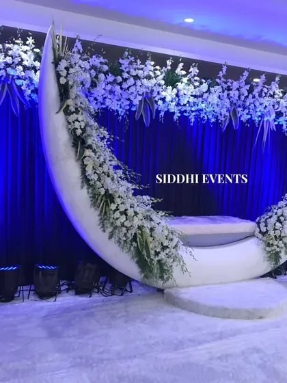 For a truly magical photo opportunity, we created this custom moon-shaped seat, adorned with delicate white florals against a deep blue backdrop, perfect for celebrating an anniversary or reception.