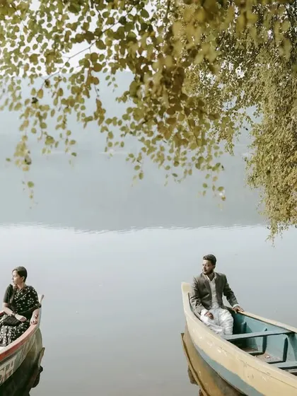 An artistic shot of the couple in separate boats, creating a visually interesting and symbolic pre-wedding photograph.