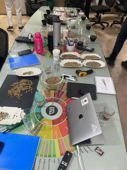 A typical setup for a coffee cupping and roasting session at our academy, with green beans, a sample roaster, and our flavor wheel.
