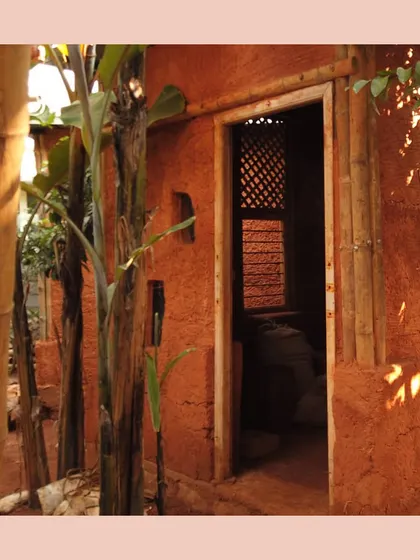 This structure is built using the ancient techniques of cob and wattle-and-daub. The thick, sculpted mud walls and bamboo-framed doorway create a space that is truly handmade and rooted in the earth.