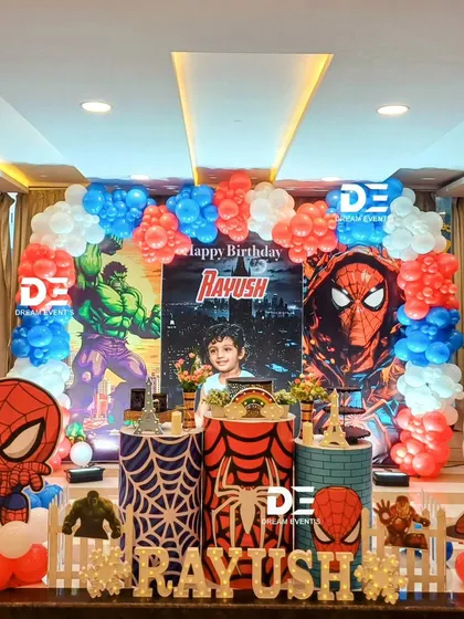 A powerful Spiderman and Avengers theme for Rayush's birthday. The decor features bold red and blue colors, character cutouts, and themed pedestals with spiderwebs and the Hulk's fist.