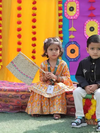 Two children sitting amidst the vibrant decor of our Baisakhi celebration. We aim to create an authentic and engaging environment for learning about different cultures.