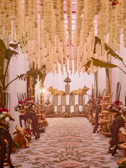 The full view of the entrance aisle, lined with traditional South Indian decor elements like banana leaves, brass cows, and hanging tuberoses.