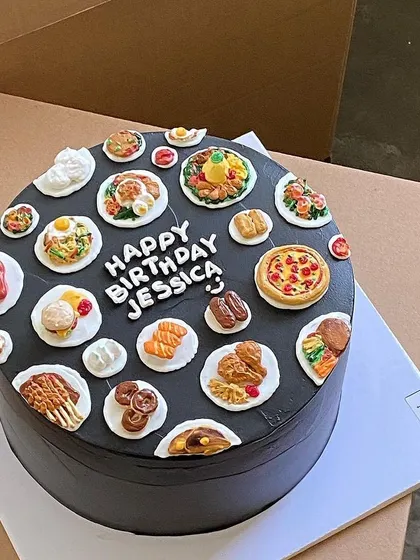 A "Happy Birthday Jessica" cake that's a feast for the eyes, covered in mini versions of pizza, burgers, salmon, and steak.