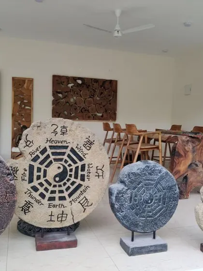 A collection of Bali-style sculptures, including Yin and Yang stone discs and other wooden art pieces.