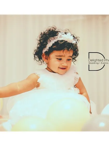 The little birthday girl playing with balloons, her curly hair and adorable expression making for a heartwarming photograph.