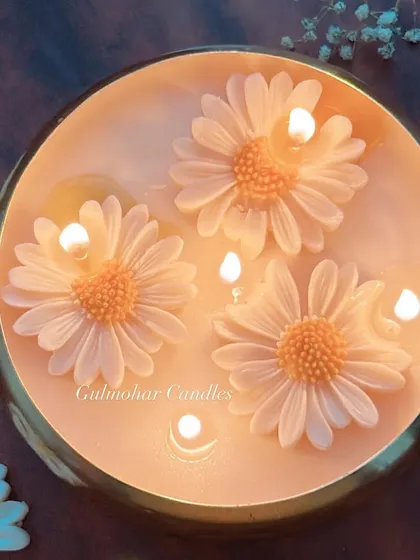 A top-down view of the daisy urli candle, lit and glowing. The wax flowers look so beautiful as they float.