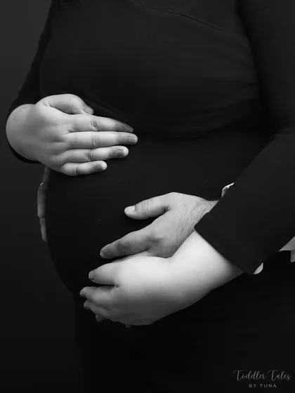 A close-up on the hands that will soon hold their baby. This shot emphasizes the shared protection and love the couple has for their unborn child.