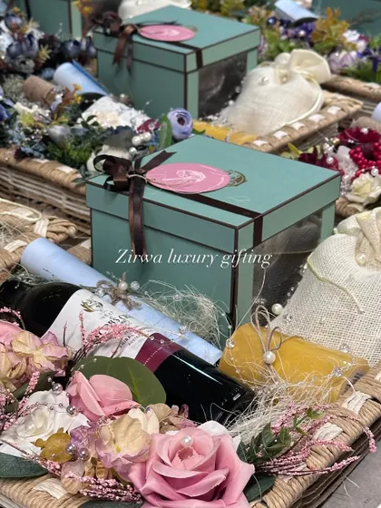 This image captures the essence of my luxury wedding hampers. A beautiful basket holds a wine bottle, gift boxes, and delicate potlis, all surrounded by floral arrangements, perfect for a wedding announcement or as a gift for the couple.
