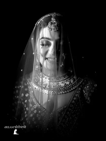 An ethereal black and white portrait of bride Nikita, her face illuminated through her sheer veil.