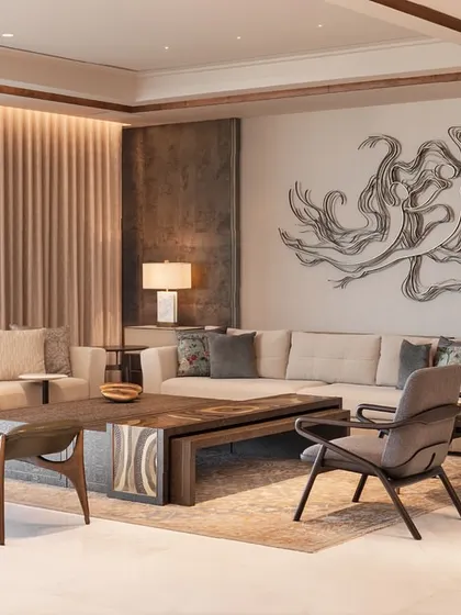 This living room is a dialogue between form, material, and art. The neutral sofas and sculptural bench are arranged to create a balanced composition, with a large metal artwork serving as a powerful backdrop.