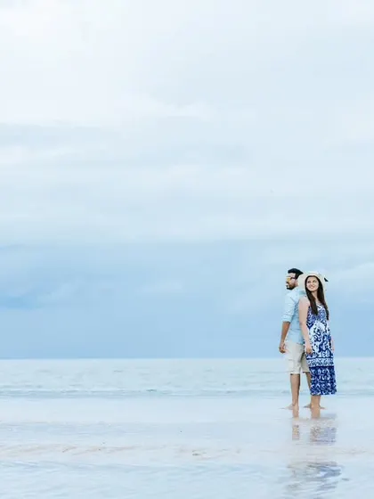 A serene pre-wedding portrait on the beach, using the vastness of the sea and sky to create a minimalist and romantic composition.