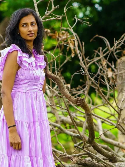 An outdoor portrait set against a rustic, natural background. The soft light and thoughtful expression give this image a serene quality.