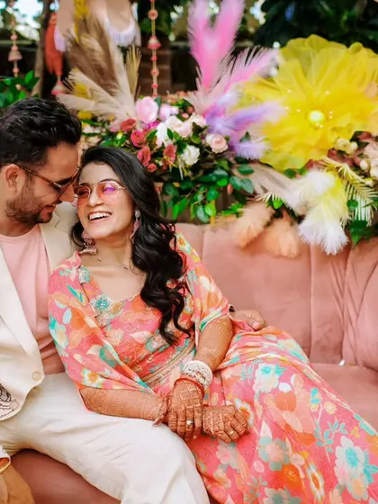 The couple shares a relaxed and happy moment on a couch during their colorful Mehendi party.