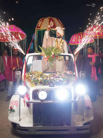 The groom's baraat entry in a decorated white jeep, complete with sparklers. This shot captures the energy and excitement of the groom's procession.