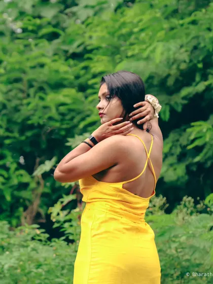 A candid-style shot from the back, set against a vibrant green wall of leaves. The yellow dress provides a beautiful color contrast.
