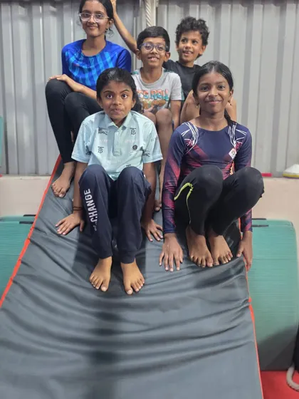 A happy group of gymnasts posing together on a cheese mat. Our classes are a place to build skills, make friends, and be part of a supportive team.