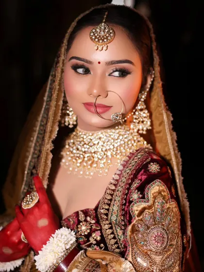 A stunning bridal look captured in dramatic lighting. The focus is on her sharp, winged eyeliner and the heavy polki jewelry, creating a regal and powerful image.