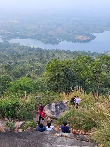 Trekkers descending a trail with a beautiful view of a lake and forest below.