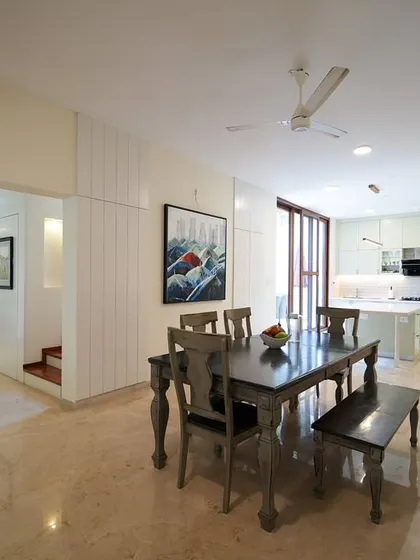 This wider view shows the seamless integration of the rustic dining area with the light, airy kitchen and the adjacent living room, creating a cohesive family space.