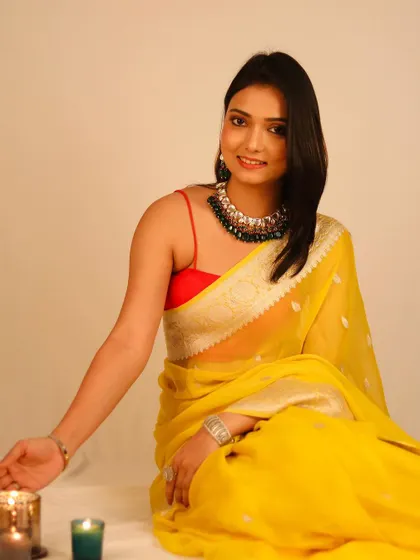 A model in a bright yellow saree seated next to candles, creating a warm, festive atmosphere perfect for a Diwali campaign or collection.