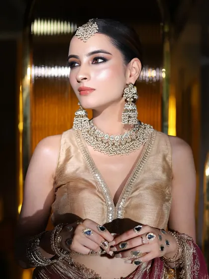 A full-length shot of a model in a gold and maroon outfit, perfect for a wedding guest or a party.