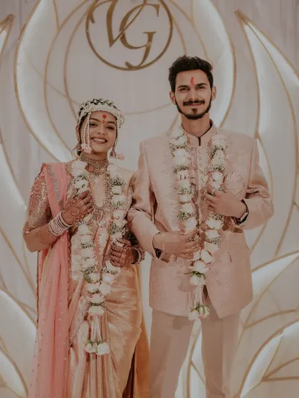 A formal portrait of the couple after their Sakhar Puda. The bride's floral mundavalya and their matching garlands complete their traditional look.